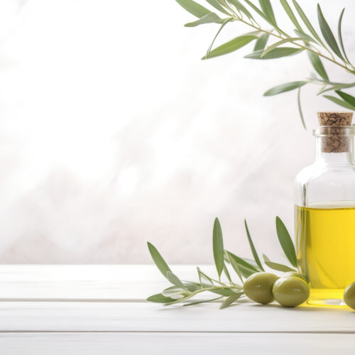 Bottle olive oil and olive branches on white wooden table over light kitchen background
