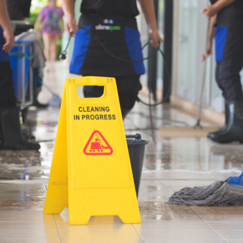 Cropped image of group of woman in protective gloves using a flat wet-mop and machine while cleaning floor